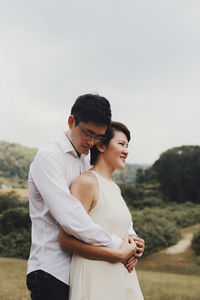 Young couple standing against sky