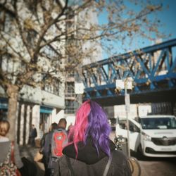 Rear view of woman with umbrella against sky in city