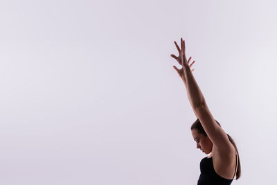 Low angle view of woman with arms raised against clear sky