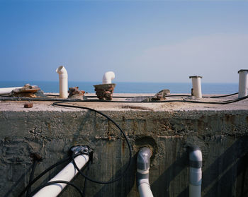 Railing by sea against clear blue sky