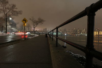 Road by illuminated city at night