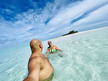 People enjoying in swimming pool against sea