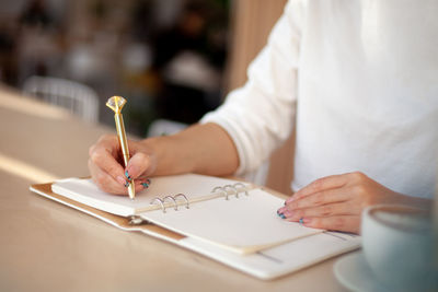 Midsection of woman holding paper with text on table