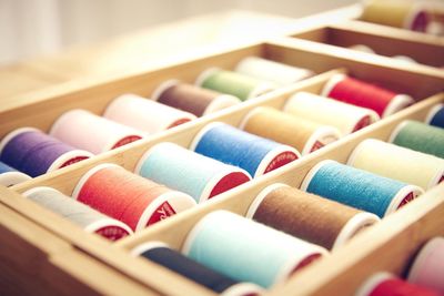 High angle view of multi colored spools in wooden box