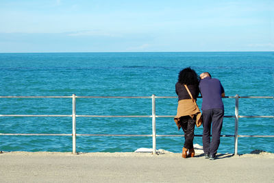 Rear view of people overlooking the sea