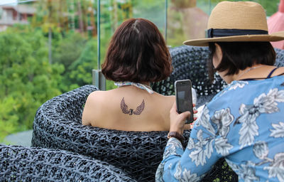 Rear view of woman photographing with mobile phone