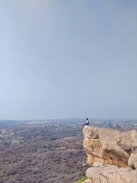 People looking at rocky mountain against sky