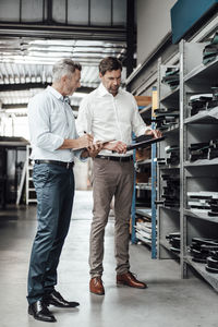 Male inspectors checking equipment while standing in workshop at industry