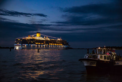 Illuminated ship in sea against sky at dusk