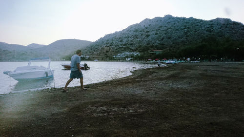 Men standing on beach by lake against sky