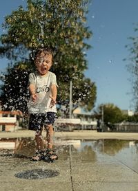 Portrait of smiling young woman standing on fountain