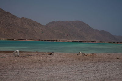 Scenic view of sea and mountains against clear sky