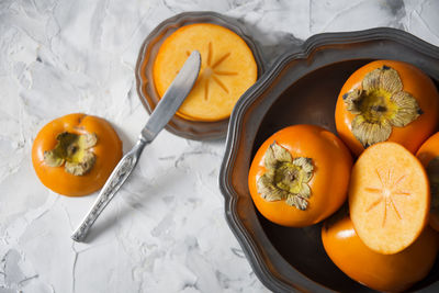 Still life with persimmon on a gray cement background in a pewter dish,