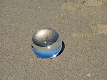 High angle view of crystal ball on sand