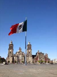 Low angle view of the mexican flag in front of metropolitan cathedral against clear sky