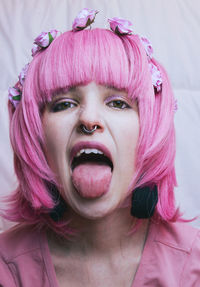Close-up portrait of young woman with pink dyed hair sticking out tongue