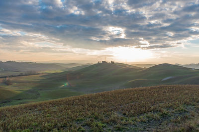 Scenic view of hills against sky at sunset