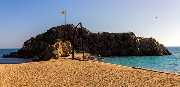 Rock formation on beach against clear sky