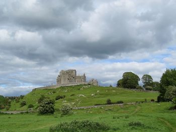 Built structure on landscape against cloudy sky