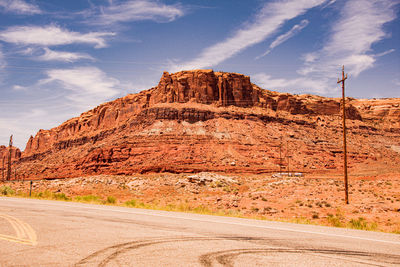 Road leading towards rocky mountains against sky
