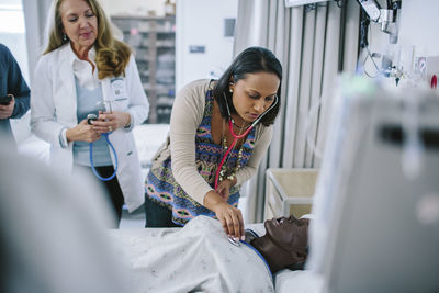 Female doctor training coworkers while examining mannequin in medical school