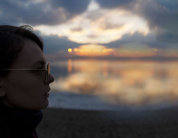 Portrait of man looking at sea against sky during sunset