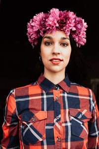 Portrait of beautiful young woman standing against black background