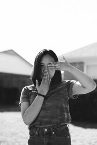 Portrait of girl gesturing while standing against sky during sunny day