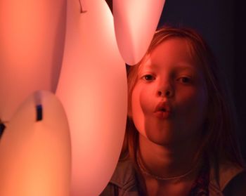 Portrait of girl blowing kiss by balloons