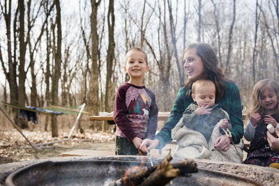 Smiling boy roasts marshmallows and looks at camera while mom smiles