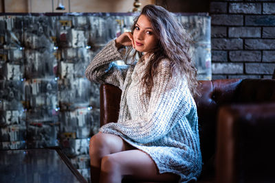 Woman looking away while sitting on wall