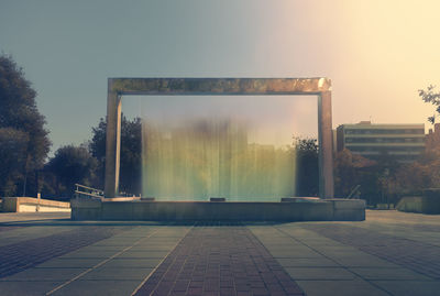 Empty street by buildings against sky during sunset