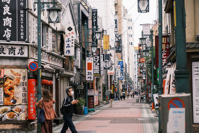 People walking on street amidst buildings in city