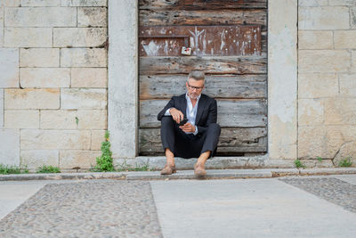 Businessman using mobile phone while sitting outdoors