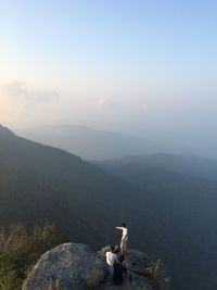 Friends at mountain peak against sky