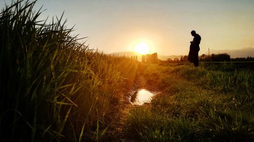 Man standing on field against sky during sunset