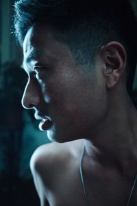 Close-up of thoughtful shirtless man in darkroom