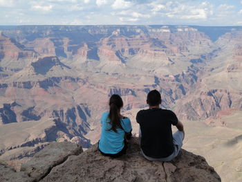 Rear view of couple relaxing on rock at grand canyon national park