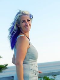 Portrait of smiling young woman standing against sea