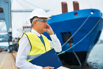 Engineer talking on mobile phone at dock