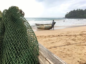 Close-up of fishing net on beach against sky