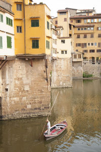 Boat in river against houses in city
