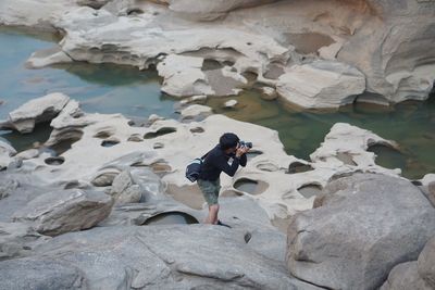 Full length of man photographing on rocks