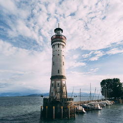 Lighthouse by sea against sky