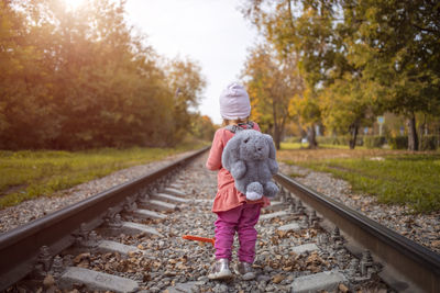 Rear view of woman standing on railroad track