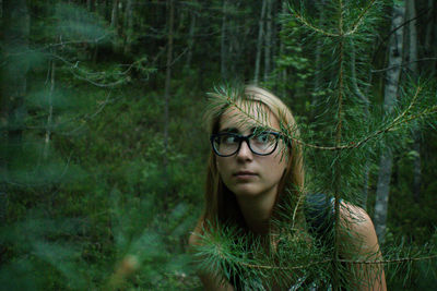 Young woman looking away while standing in forest