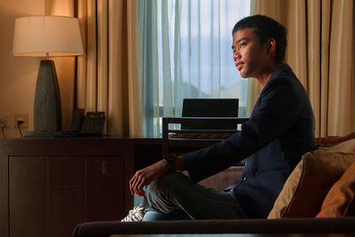 Side view of man sitting on sofa at home