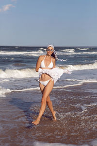 Woman run in a white bathing suit and hat sunglasses on an empty sandy beach