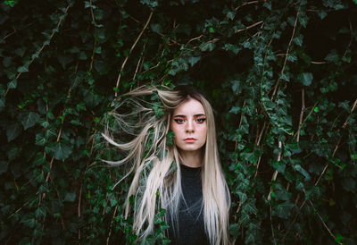 Portrait of beautiful young woman standing by plants