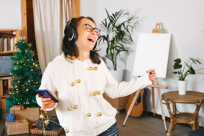 Portrait of young woman using mobile phone while sitting at home